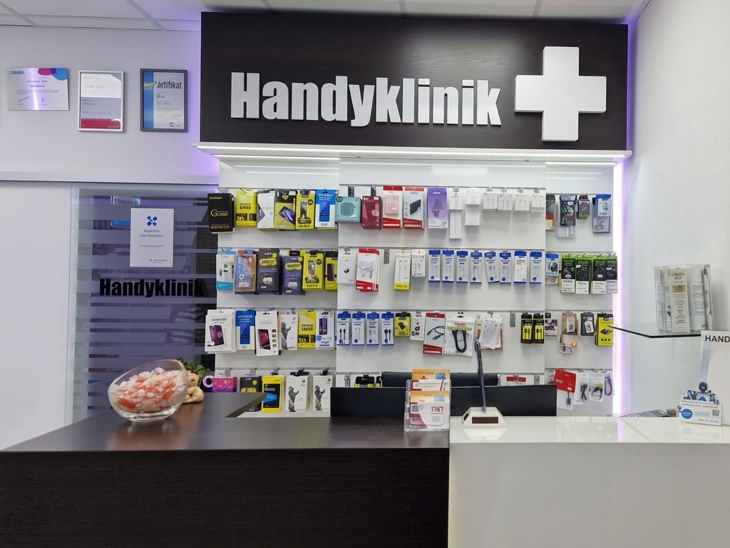 Empfangstheke der TWT Handyklinik in Wenden mit dem Handyklinik-Schild über der Zubehörwand